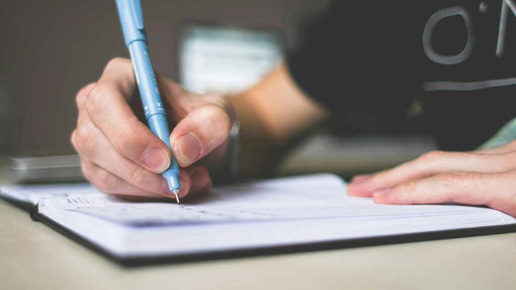 Ragazzo che scrive con la biro sul quaderno