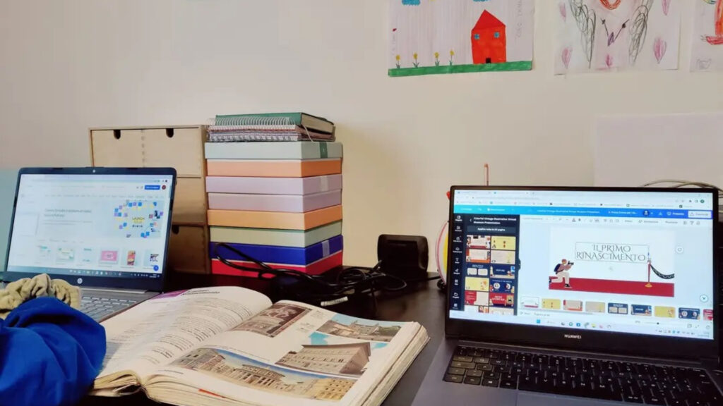 Scrivania di un bambino con due computer e un libro per lo studio
