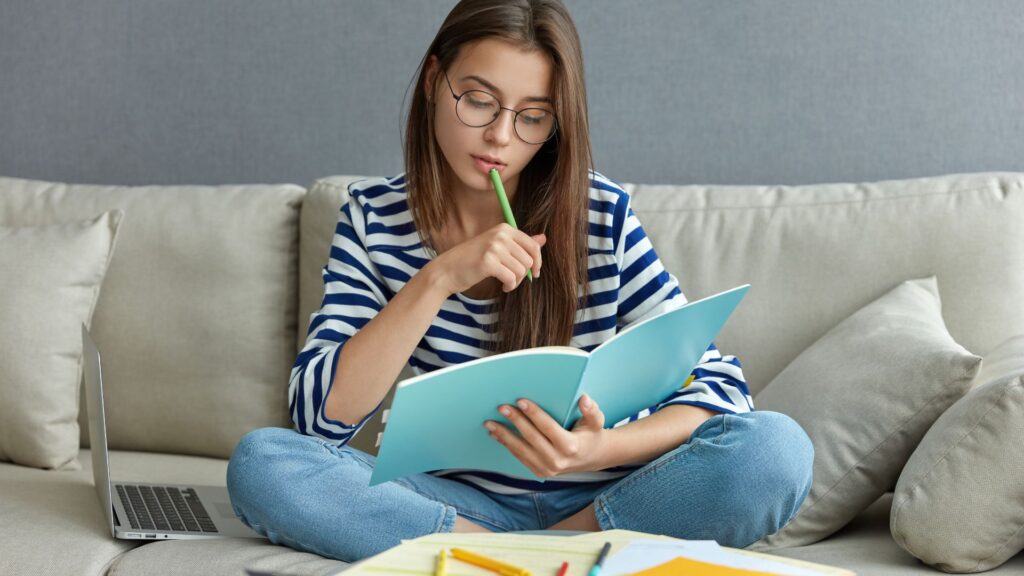 Ragazza sul divano usa una tecnica di apprendimento per studiare un libro